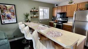 Una cocina moderna con armarios de madera, electrodomésticos de acero inoxidable y una isla central con sillas.