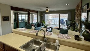 Una cocina con una isla grande, un lavamanos doble y vistas al exterior a través de amplios ventanales.