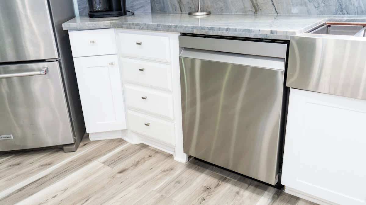 Una cocina con armarios blancos, electrodomésticos de acero inoxidable y encimera de mármol.