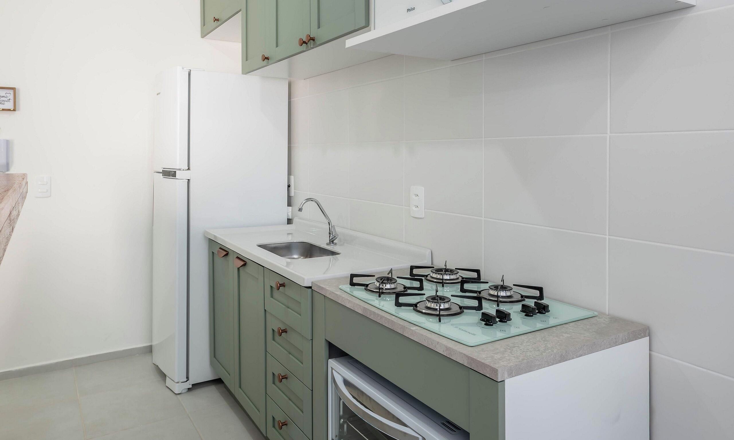 A kitchen with a built-in gas stove, a sink, and a white refrigerator.