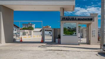 A beach club entrance with a gated driveway, a clear sky, and a building in the background.
