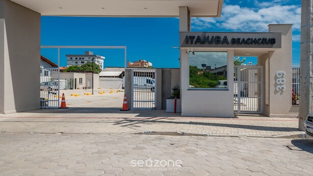 A beach club entrance with a gated driveway, a clear sky, and a building in the background. - Apart w/ BBC 750 m From the Beach Sfr0411 (Barra Velha)