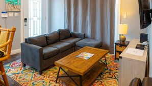 Una sala de estar moderna con un sofá gris, una mesa de centro de madera y una alfombra colorida.