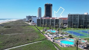 Un complexe hôtelier doté de plusieurs piscines, d’une plage et de bâtiments de grande hauteur en arrière-plan.