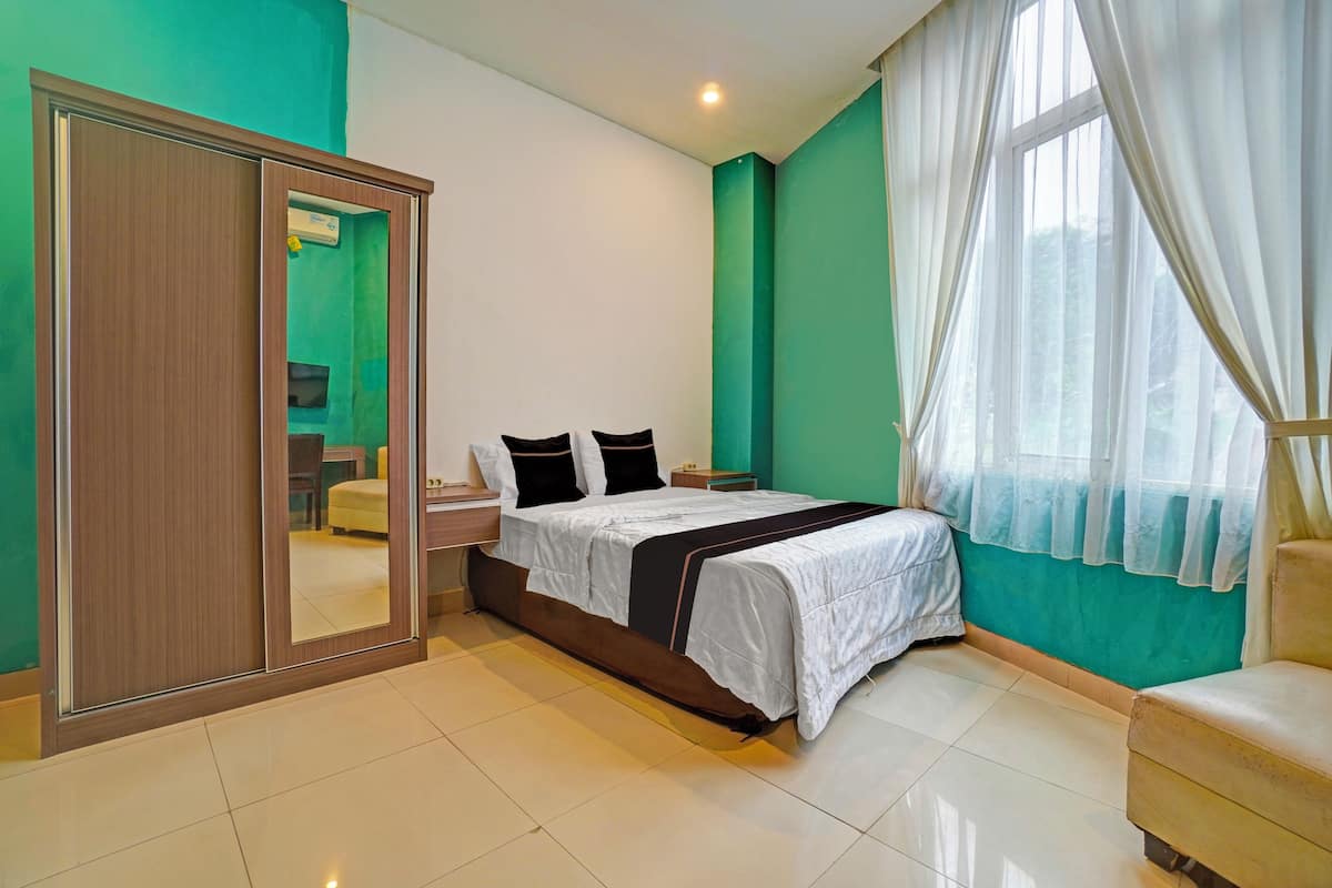 Un dormitorio con cama, armario, mesita de noche y ventana con cortinas.