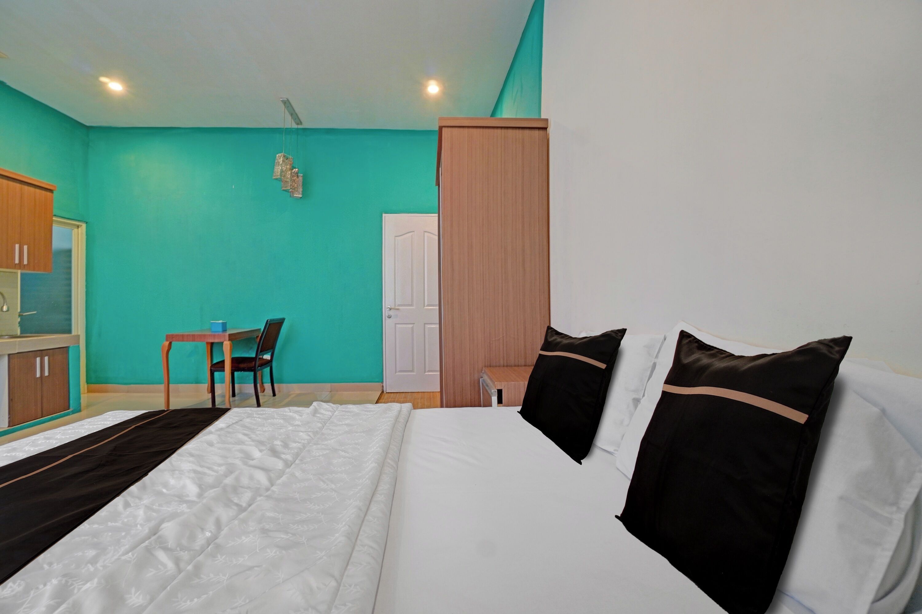 A hotel room with a bed, a desk, a chair, and a wardrobe.