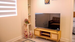 Ein Wohnzimmer mit Flachbildfernseher, einer Holz-Unterhaltungseinheit und dekorativen Vasen.