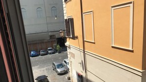 A narrow street with parked cars and a building with a sign reading "BASILICA PIA DI SAN LORENZO". - Lovely studio apartment in the heart of the historic center of Rome (Roma)