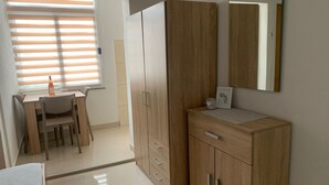 A modern bedroom with a wooden wardrobe, a bedside table, and a window with blinds. - Apartments Adriana Studio apartment 8 (Podaca)