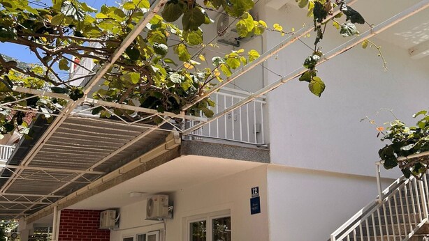 A two-story building with a white exterior, a red brick wall, and a balcony with a white railing. - Apartments Adriana Studio apartment 3 (Podaca)