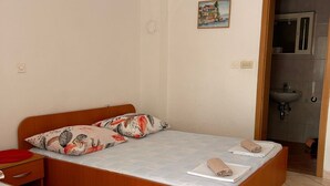 A bedroom with a wooden bed, two pillows, a red side table, and a bathroom visible through an open door. - Apartments Adriana Studio apartment 3 (Podaca)