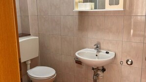 A small bathroom with a toilet, sink, and a mirror above the sink. - Apartments Adriana Studio apartment 3 (Podaca)