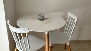 A round white table with a candle, two white chairs with wooden legs, and a plain wall. - Apartments Adriana Studio apartment 4 (Podaca)