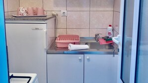 Een kleine keukenhoek met een koelkast, een gootsteen en een aanrecht.
