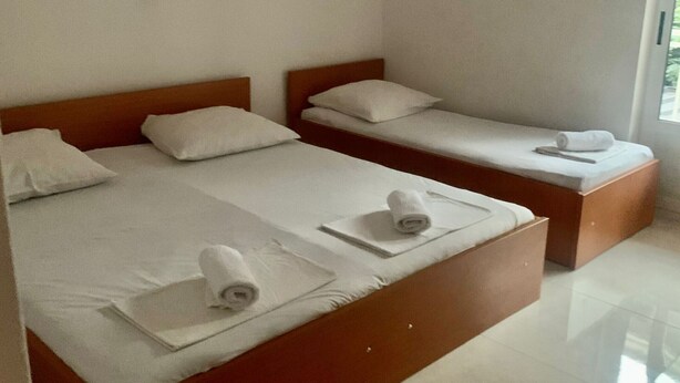 Een hotelkamer met twee eenpersoonsbedden, elk met een houten hoofdeinde, witte lakens en opgerolde handdoeken.