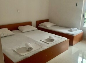 A hotel room with two single beds, each with a wooden headboard, white linens, and rolled towels. - Apartments Adriana - Two bedroom apartment 57 (Podaca)