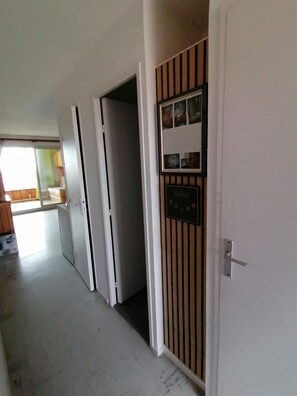 Ein Flur mit einer Tür rechts, einem Kleiderschrank links und einem Blick auf einen Raum mit Bett und Fenster.