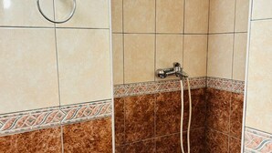 Casa de banho com azulejos bege e castanhos, chuveiro com chuveiro manual e porta-toalhas.