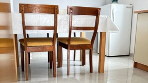 Zwei Holzstühle mit gepolsterten Sitzflächen und Rückenlehnen stehen an einem Tisch in einer Küche mit einem weißen Kühlschrank und Fliesenboden.
