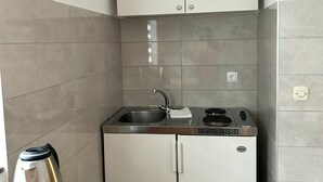 Eine kompakte Küchenzeile mit Spüle aus Edelstahl, einem Herd und einem kleinen Kühlschrank.