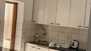 A kitchen with white cabinets, a gas stove, a kettle, and a bottle of Fairy dishwashing liquid. - Apartments Adriana - Two bedroom Apartment Ružica 2 (Podaca)