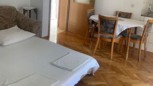 A bedroom with a large bed, a wooden dining table with chairs, and a small side table. - Apartments Adriana - Two bedroom Apartment Ružica 2 (Podaca)
