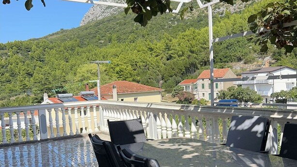 A terrace with a mosaic floor, outdoor seating, and a view of a hillside with buildings. - Apartments Adriana - Two bedroom Apartment Ružica 2 (Podaca)