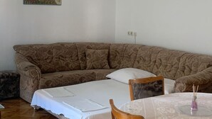 A living room with a patterned sofa, a small table with a vase, and a painting on the wall. - Apartments Adriana - Two bedroom Apartment Ružica 2 (Podaca)