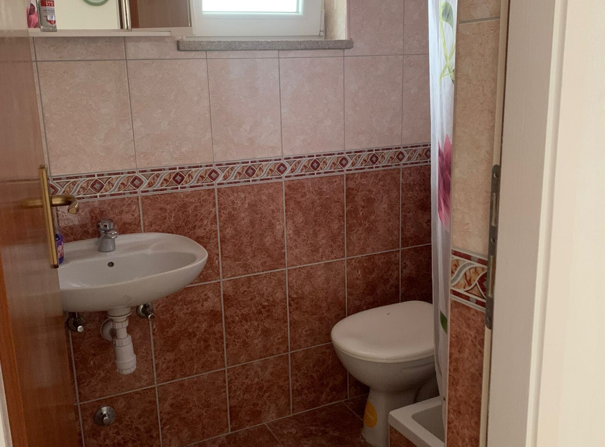A bathroom with a sink, toilet, and a window above the sink.