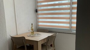 Un coin repas avec une table en bois et quatre chaises, une bouteille de vin et deux verres à vin posés sur un set de table.