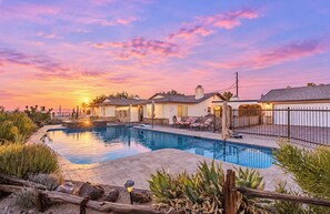 A swimming pool with a patio area, a fence, and houses in the background. - Pool Home w/ Spa, Blackstone, Ping Pong & Dog Friendly! (Bullhead City)
