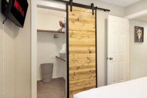 A room with a sliding door, a trash can, a shelf with items, and a wall-mounted sign.