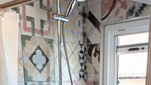 Een douche met een handdouche en een glazen deur.