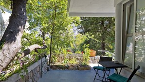 Un patio con una mesa y sillas, un muro de piedra y vistas a una ladera.