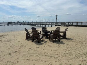 A beach with wooden Adirondack chairs arranged around a table, a pier extending into the water, and a clear sky. - Comfy and Cozy @ Kingsmill - Studio close to Busch Gardens & Colonial Wmsburg (Williamsburg)