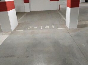 Eine Parkgarage mit weißen Säulen und roten Streifen, deren Boden mit der Nummer 2-141 gekennzeichnet ist.