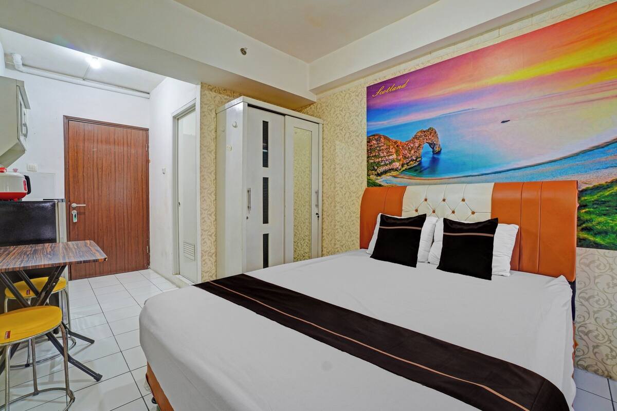 Ein Hotelzimmer mit einem Bett, einem Schreibtisch und einem Stuhl. Es gibt einen Kleiderschrank und ein Bild an der Wand.