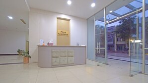 A reception area with a reception desk, a sign reading "Pinus Residence," and a glass door leading outside. - OYO 95064 Gunung Putri Skyland (Gunung Putri)