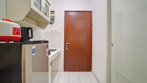 A narrow hallway with a refrigerator, a sink, and a wooden door. - OYO 95064 Gunung Putri Skyland (Gunung Putri)