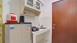 A compact kitchen with a refrigerator, a stove, and a sink. - OYO 95064 Gunung Putri Skyland (Gunung Putri)