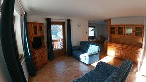 A spacious living room with a sofa, a television, and wooden cabinets. - Baita la Malgheta - Bormio, mountains, skiing and relaxation (Piatta)