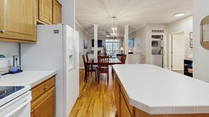 Una cocina moderna con armarios de madera, un refrigerador blanco y una zona de comedor con mesa y sillas.