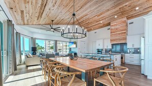 A spacious kitchen with white cabinets, a wooden dining table, and wicker chairs. - Amazing Beachfront Home, Incredible Views, Heated Pool, Hot Tub, Elevator! (Destin)