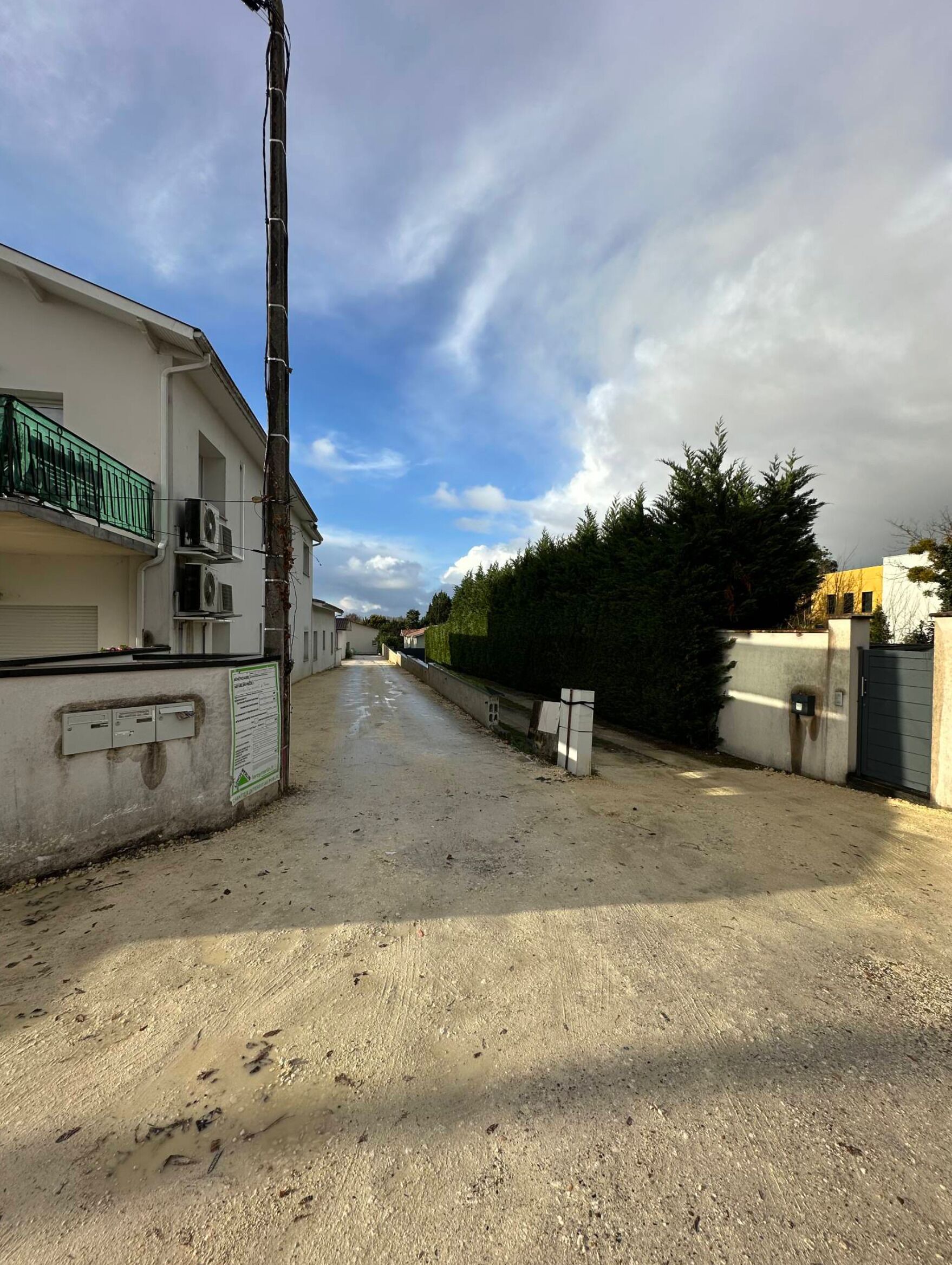 Une rue résidentielle bordée de maisons, avec un poteau électrique et un ciel dégagé.