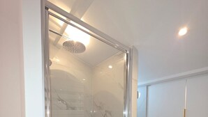 A modern bathroom with a glass-enclosed shower, marble tiles, and a wooden floor. - Charming exceptional house on the outskirts of Bordeaux (Eysines)