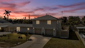 A two-story house with a garage, a driveway, and a well-maintained lawn. - Spacious 5BR Duplex Near Beach and IMG - Ideal for Multi-Family Vacations (Cortez)