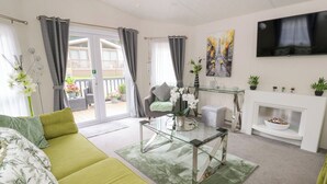 A modern living room with a sofa, a glass coffee table, a fireplace, and a TV mounted on the wall. - The Haven (New Quay)