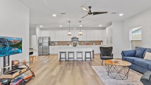 Una cocina moderna con armarios blancos, electrodomésticos de acero inoxidable y una isla central con taburetes de bar.