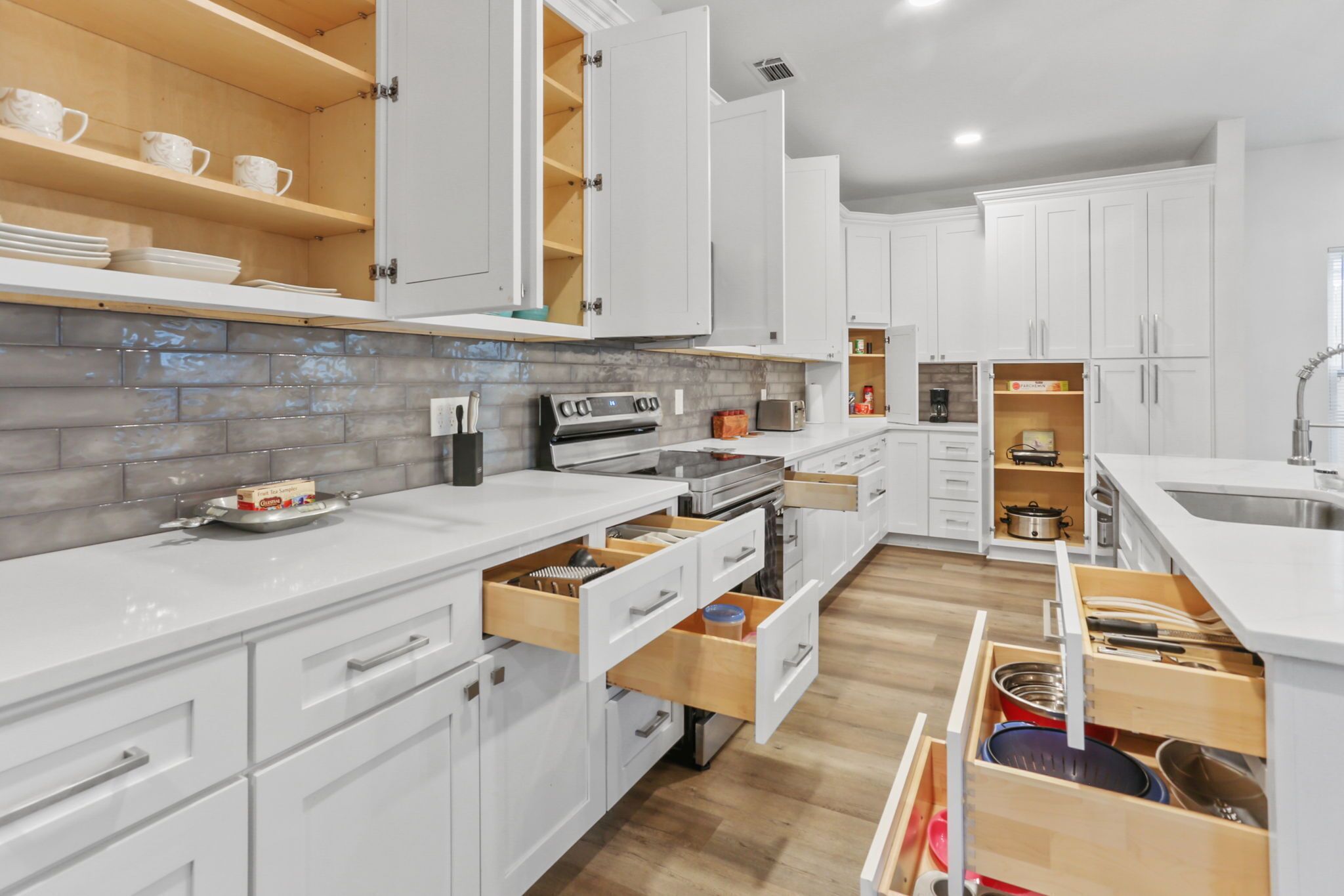 Una cocina moderna con armarios blancos, repisas de madera y un revoque de azulejos.