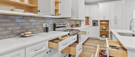 Una cocina moderna con armarios blancos, repisas de madera y un revoque de azulejos.